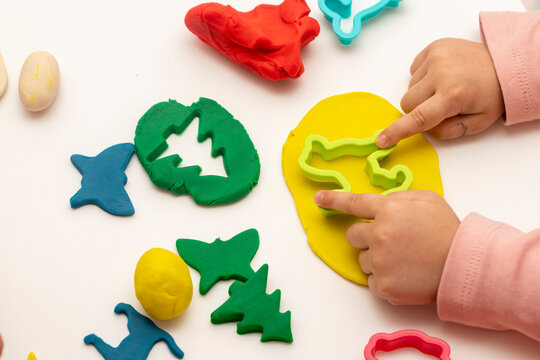 Girl playing dough with her mother. mother and daughter playing on a white background. Making various shapes with dough. Close-up. Mothers Day