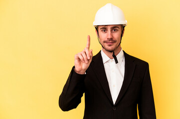 Young architect caucasian man isolated on yellow background showing number one with finger.