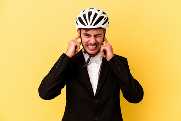 Young caucasian business man wearing a bike helmet isolated on yellow background covering ears with hands.
