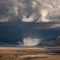 Spectacular view of the mountains. A rare natural phenomenon. Atmospheric precipitation virga. Epic cumulus clouds. Panoramic view. Autumn in Kurai. Altai Republic.