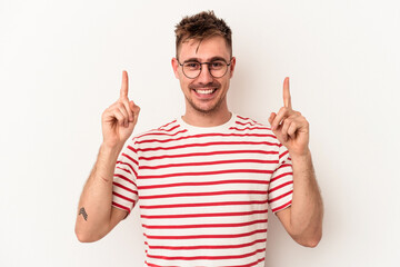 Young caucasian man isolated on white background indicates with both fore fingers up showing a...