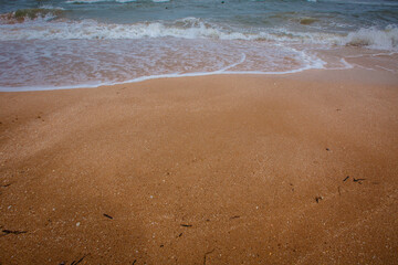 waves close-up on the sand during the day when the sky is a little cloudy.