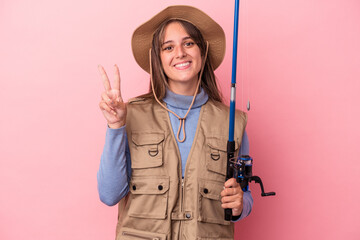 Young caucasian fisherwoman holding a rod isolated on pink background showing number two with fingers.