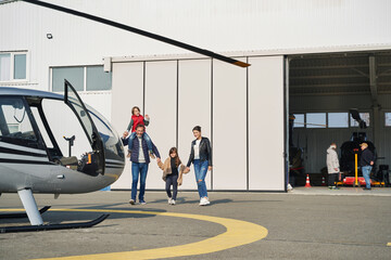 Lovely family with kids walking on an airfield together