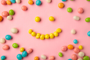 Colorful chocolate candy pills on pink background.