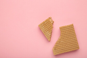 Square chocolate wafe biscuit broken on pink background.