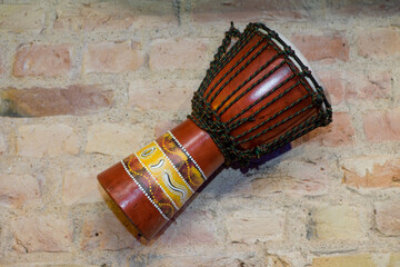 A djembe or jembe. Traditional african drum. Brick wall.