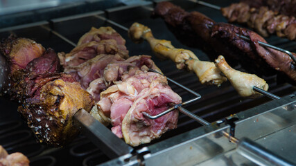 Different meats are cooked on skewers on electric grill in restaurant.