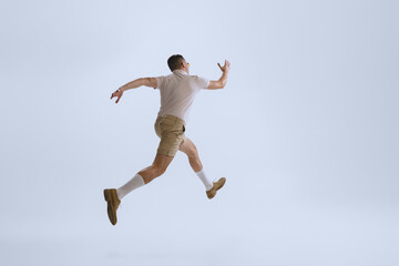 Obraz na płótnie Canvas Dynamic portrait of young man dressed in 50s, 60s style running away isolated on white background. Retro vintage style