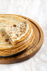 Vertical image of stack of delicious west pancakes on the wooden board,kitchen white marble table
