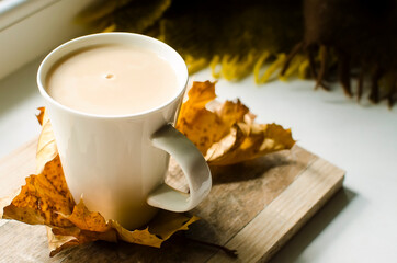 autumn cozy still life with a cup of coffee with milk and yellow autumn leaves. Autumn background for articles and blog.