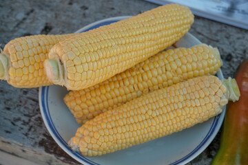 corn in a bowl close-up top view. Raw fruit and vegetables. White plate
