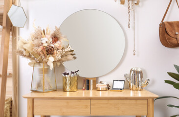 Modern wooden dressing table with decorative elements and makeup products in room