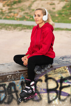 Vertical photo of a woman listening to music with headphones in skate park