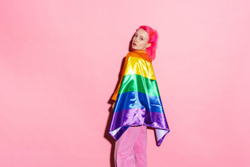 Shirtless woman looking at camera while posing with rainbow flag