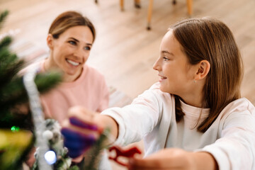 White mother and daughter decorating christmas tree together