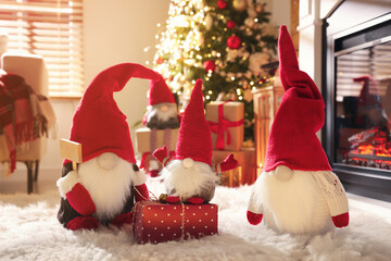 Cute Christmas gnomes and gift in room with festive decorations