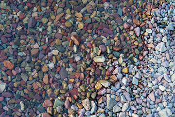 Colored stone pebbles and rocks in the crystal clear water Lake McDonald in Glacier National Park, Montana at sunset on a summer evening - near Columbia Falls/Kalispell/Whitefish/Hungry Horse
