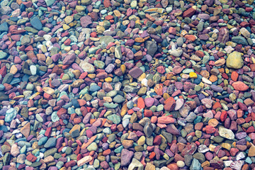 Colored stone pebbles and rocks in the crystal clear water Lake McDonald in Glacier National Park,...