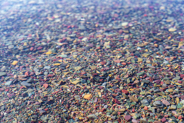 Colored stone pebbles and rocks in the crystal clear water Lake McDonald in Glacier National Park, Montana at sunset on a summer evening - near Columbia Falls/Kalispell/Whitefish/Hungry Horse