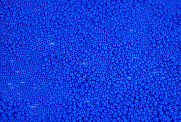 The texture of the surface of scattered blue beads for needlework. Beads for women's needlework....