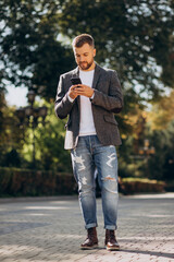 Fototapeta premium Handsome young business man using phone outside the street