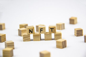 Word NFT (non fungible token) written on the wood cubes on white  background. Non-fungible tokens  concept NFT.