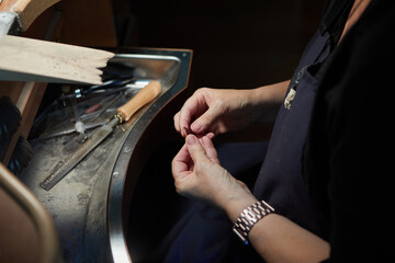 close up of the hands of an artisan woman adjusting handmade jewel