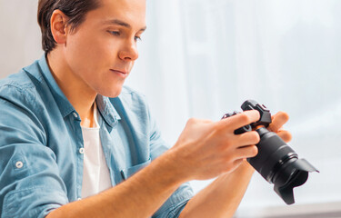 Freelance photographer's workplace. A young man with a camera is sitting at a table and watching photos. Remote work concept.