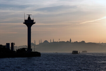 Silhouette of Historical Istanbul behind a high tech radar tower at sunset with boats at sea.