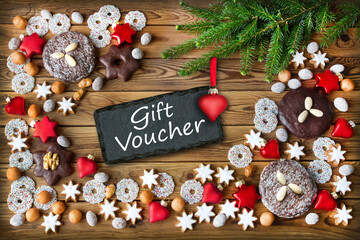 Gift Voucher and Christmas biscuits with red hearts on wooden background