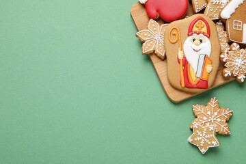 Tasty gingerbread cookies on green background, flat lay with space for text. St. Nicholas Day...