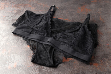 Black set of women's underwear on textured background