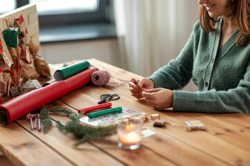 winter holidays and hobby concept - woman with decorated tag making advent calendar on christmas at home