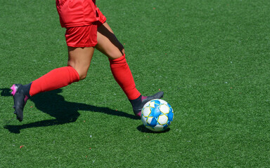 Woman football player kicking ball on a soccer field