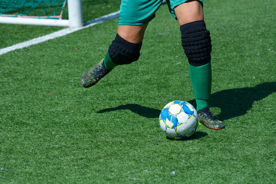 Woman goalkeeper kicking ball in front of a football goal on a soccer field
