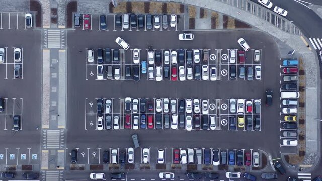 Aerial top view of many cars parked. Drone View over Outdoor Parking Lots. Car finds parking spot. Car parking of a shopping center, top-down aerial shooting. 