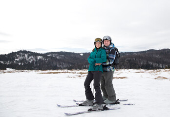 Fototapeta na wymiar loving couple poses for a photo before skiing on a snowy mountain slope. Drive to a mountain resort on Valentine's Day. joy of relationship. Interesting active winter recreation, digital detox