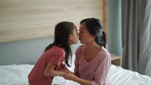 Lovely Asian mom and daughter fooling on the bed