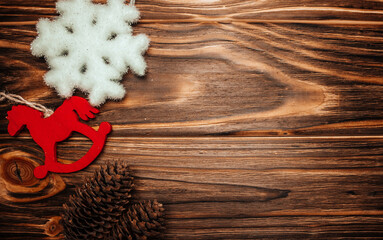 Christmas decorations and pine cones on wood brown background with fluffy snowflakes