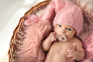 Adorable newborn baby with pacifier in wicker basket, top view
