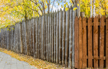 Wooden fence made of vertical boards in the park in autumn.
