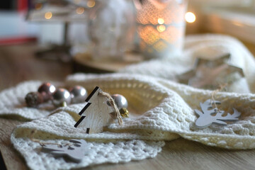 Various Christmas decorations in neutral colors, soft knitted blanket and lit candles. Selective focus.