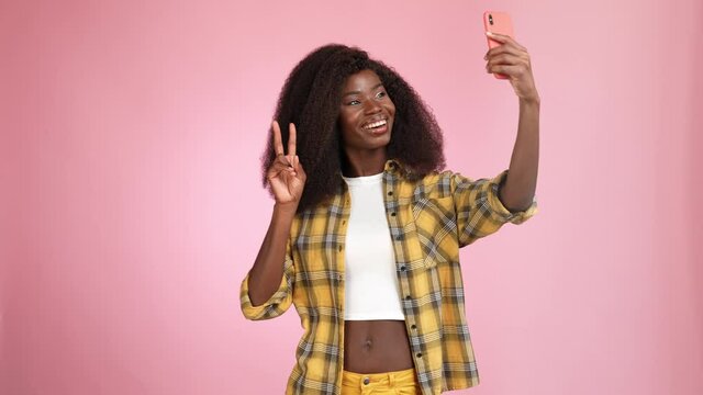 Lady make selfie gadget show v sign blow kiss isolated pink color background