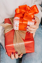 Women's hands give a handmade gift wrapped in paper with a black ribbon.