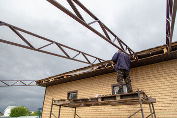 A worker installs metal spans at a construction site.