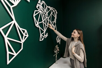 Smiling saleswoman touching world map on wall in office