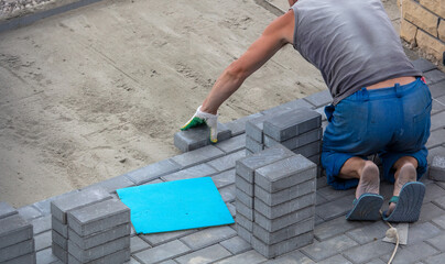 A worker is laying paving slabs in the yard. Construction
