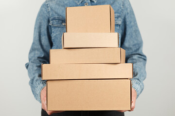 A stack of cardboard boxes in the hands of a courier. Delivery of parcels, many purchases.