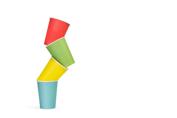 Vasos de bebida de papel de colores desechables apilados sobre fondo balnco liso y aislado. Vista de frente. Copy space